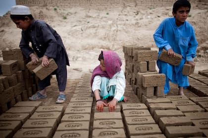 KABUL, AFGHANISTAN - MAY 14: Afghan children sorts bricks at the Sadat Ltd. Brick factory, where they work from 8am to 5 pm daily, on May 14, 2010 in Kabul, Afghanistan. Child labour is common at the brick factories where the parents work as labourers, desperate to make more money enlisting their children to help doing the easy jobs. Brick factories are an economical, business that is still thriving. The land used is dry and barren which is perfect for the making of bricks providing work almost all the year round. A few years ago all factories changed from wood to coal causing further problems with pollution. The factories have been pushed out of the city limits because of this issue. Workers can make an average of USD 200 to 300 per month. For 1,000 bricks the factory will get about USD 45. (Photo by Majid Saeedi/Getty Images)