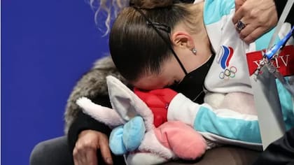 Kamila Valieva, de 15 años, llora abrazada a su conejo de peluche al recibir el puntaje que la ubica en el cuarto lugar de la competencia y la deja fuera del medallero tras dos duras caídas y una performance que no convenció