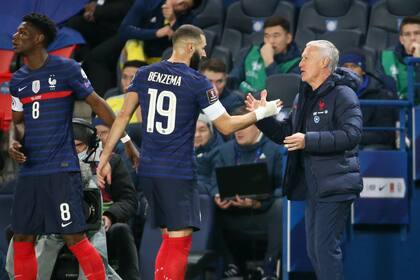 Karim Benzema se saluda con Didier Deschamps en un partido de la eliminatoria para Qatar 2022; justo antes del Mundial, el delantero quedó fuera del torneo y después de la final se retiró de la selección de Francia, pero ahora está dispuesto a volver.