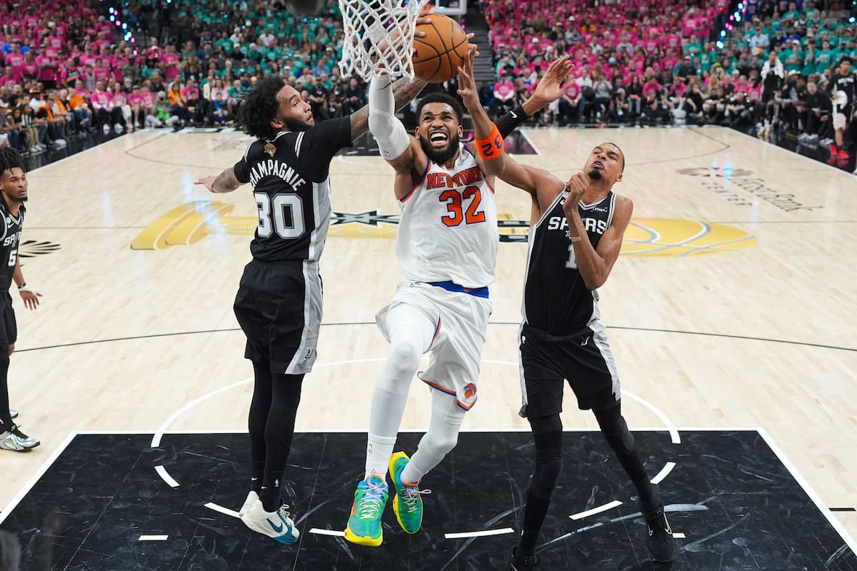 Karl-Anthony Towns, de los Knicks de Nueva York, encesta entre Victor Wembanyama y Julian Champagnie, de los San Antonio Spurs