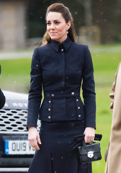 Kate eligió una chaqueta de espiración militar y falda midi, ambos de Alexander McQueen, para visitar el Centro de Rehabilitación Stanford Hall. La mini shoulder bag pertenece a la misma firma