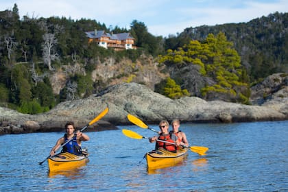 Kayak en el lago Nahuel Huapi, con la hostería de fondo.