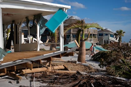 Kery Flynn, a la derecha, y su amigo caminan frente a una casa dañada con el techo destruido tras el paso del huracán Milton, el 13 de octubre de 2024, en Manasota Key, en Englewood, Florida. (AP Foto/Rebecca Blackwell, Archivo)