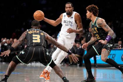 Kevin Durant (7), de los Nets de Brooklyn, conduce el balón y encara a Terry Rozier (3) y Kelly Oubre Jr. (12), de los Hornets de Charlotte, durante la segunda mitad del juego de baloncesto de la NBA, el miércoles 7 de diciembre de 2022, en Nueva York. (AP Foto/John Minchillo)