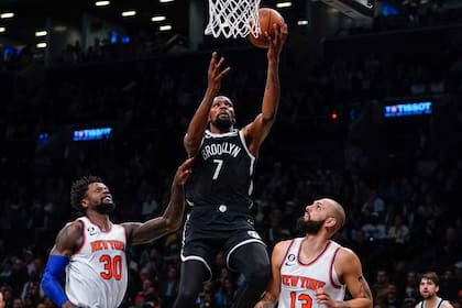 Kevin Durant, de los Nets de Brooklyn, encesta entre Julius Randle y Evan Fournier, de los Knicks de Nueva York, el miércoles 9 de noviembre de 2022  (AP Foto/Frank Franklin II)
