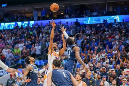 Kevin Durant, de los Suns de Phoenix, atrás en el centro, tira la canasta ganadora del partido sobre los Mavericks de Dallas, ante el intento de bloqueo de Tim Hardaway Jr., derecha, y Kyrie Irving, izquierda, durante la segunda mitad del juego de baloncesto de la NBA, el domingo 5 de marzo de 2023, en Dallas. (AP Foto/Gareth Patterson)