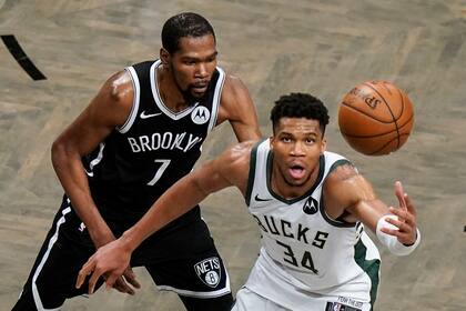Kevin Durant (izquierda) de los Nets de Brooklyn defiende contra Giannis Antetokounmpo durante el tiempo extra del séptimo juego de la serie de segunda ronda de los playoffs de la NBA, el sábado 19 de junio de 2021, en Nueva York. (AP Foto/Frank Franklin II)