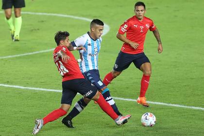 Kevin Gutiérrez, mediocampista central de Racing, maniobra ante dos futbolistas de Independiente.