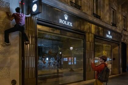 Kevin Ha alcanza un interruptor de luz afuera de una tienda Rolex en los Campos Elíseos en París, el 23 de septiembre de 2022. (Mauricio Lima/The New York Times)