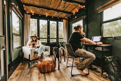 Kris y Andy trabajando y disfrutando del interior de su casa rodante, hasta con perro y plantas