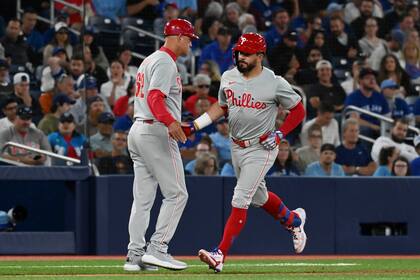 Kyle Schwarber (derecha), de los Filis de Filadelfia, festeja con el coach de la antesala Dusty Wathan, luego de batear un jonrón en el cuarto inning del juego ante los Azulejos de Toronto, el jueves 3 de septiembre de 2024 (Jon Blacker/The Canadian Press via AP)