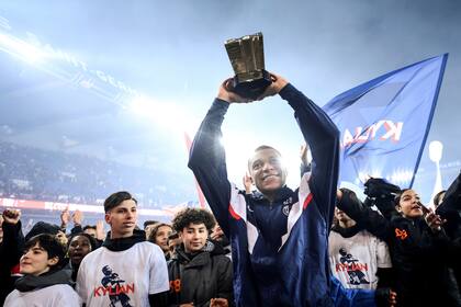 Kylian Mbappé, delantero del París Saint-Germain, alza el trofeo que lo acredita como máximo goleador en la historia del equipo, el sábado 4 de marzo de 2023 (Franck Fife/Pool Photo via AP)