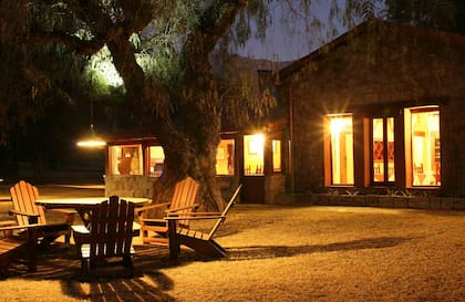 El jardín de La Granadilla junto a la casa con las luces encendidas por la noche.