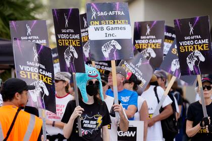 La actriz Sena Bryer, de izquierda a derecha, con otros manifestantes en una manifestación de la huelga de actores de videojuegos del sindicato SAG-AFTRA frente a los estudios Warner Bros. el miércoles 28 de agosto de 2024 en Burbank, California. (Foto AP/Chris Pizzello)