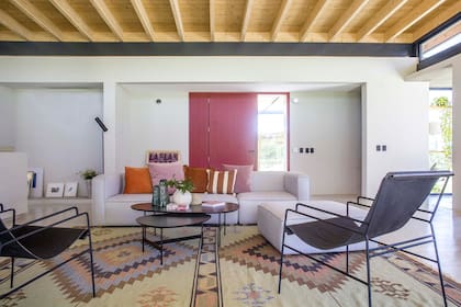 La alfombra (Kalpakian) fue un punto de partida: “Buscaba una alfombra divertida, y de su paleta surgió el resto de la ambientación”. Sillón (South Design). Almohadones, floreros y sillas de hierro con asiento de cuero negro (todo de Johann Home & Deco). Mesas de centro ‘Mariposa’ (Good Luck Casa).