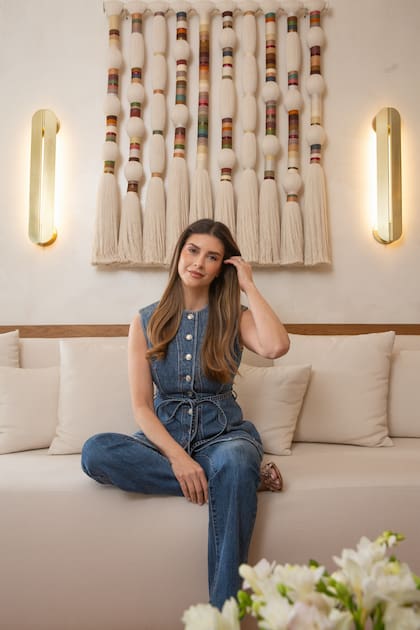 La anfitriona posa en un ambiente que refleja elegancia moderna y arte contemporáneo. Detrás de ella, una obra de la artista Cristina Codern