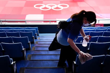 La Argentina competirá en varias disciplinas de los Juegos Olímpicos Tokio 2020 este miércoles 28. En foto: una trabajadora desinfecta las butacas de la arena Nippon Budokan de Judo en la capital japonesa. (AP Foto/Jae C. Hong, Archivo)