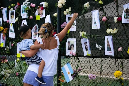 La argentina Victoria Mayer y su hijo Antonio en el memorial en Surfside, con las imágenes de una de las argentinas desaparecidas en el derrumbe