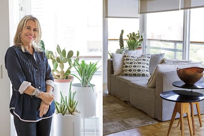 La arquitecta Diana Reisfeld posa junto a macetas con pie blanco de Solsken. A la derecha, un mullido sillón de dos cuerpos con almohadones (Landmark) y mesas auxiliares.