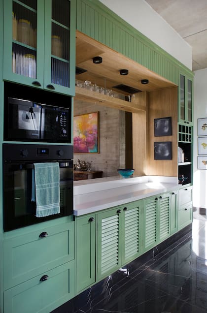 La arquitecta Inés Fuseo quería una cocina bien cálida. Hizo los frentes reciclando y pintando de verde los originales, agregó tiradores cubeta negro y vidrio acanalado para las alacenas.