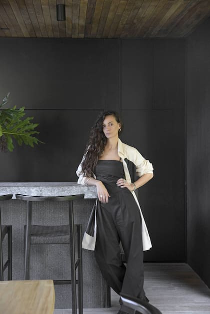 La arquitecta Paula Rodríguez Donati, al frente de Brava Arquitectura y de este proyecto. Barra revestida en granito negro texturado con tapa de granito ‘Boreal’ diamantado, otro diseño del Estudio realizado por Aranda Mármoles. Banquetas (Marini Estudio).