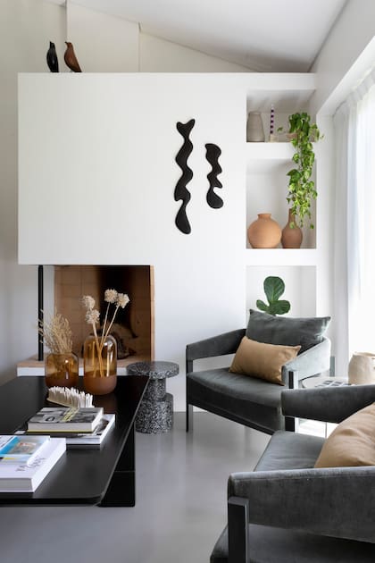 La arquitecta Sara Plazibat cerró el frente de la chimenea para colgar la obra en madera de kiri de Agustín Leiro y crear nichos para objetos decorativos, como los jarrones de arcilla (Philippa Deco Boutique).