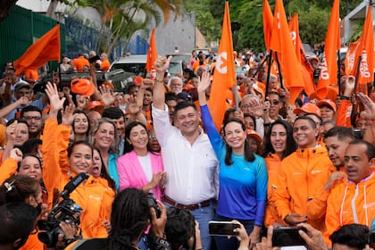 La aspirante presidencial María Corina Machado y el líder opositor Freddy Superlano saludan con los brazos en alto durante un evento de campaña en Caracas