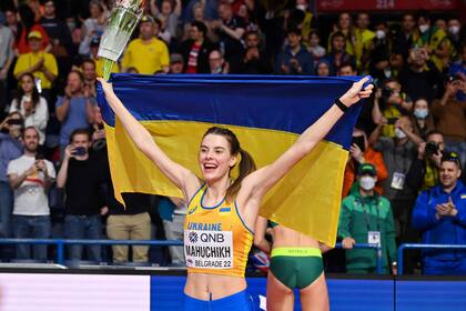 La atleta Yaroslava Mahuchikh festejando su victoria portando la bandera ucraniana