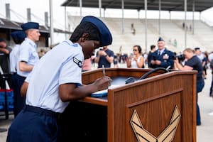 La aviadora de primera clase D'elbrah Assamoi, de Costa de Marfil, firma su certificado de ciudadanía estadounidense al final de una ceremonia de entrenamiento militar básico en la Base Conjunta San Antonio-Lackland, el 26 de abril de 2023, en San Antonio, Texas. (Vanessa R. Adame/Fuerza Aérea de Estados Unidos vía AP)