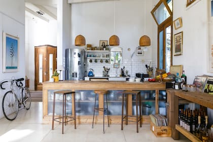 La barra de madera y vidrio esmerilado limita la cocina, ofrece espacio de guardado y es comedor, gracias a las tres banquetas de hierro y madera (Bobby Rastalsky).