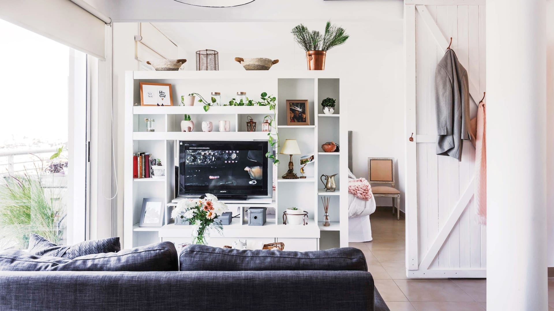 La biblioteca fue el primer mueble que compró: ayuda a organizar los espacios, tener privacidad en el dormitorio y bloquear un poco la luz. Y le hizo una genial base giratoria para el televisor.