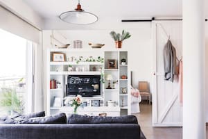La biblioteca fue el primer mueble que compró: ayuda a organizar los espacios, tener privacidad en el dormitorio y bloquear un poco la luz. Y le hizo una genial base giratoria para el televisor.