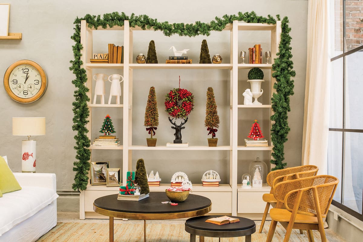 La biblioteca, rodeada con muérdagos, intercala adornos navideños con los deco existentes. Se destacan los arbolitos de peluche con luces, la grulla de cerámica, una corona con frutos del bosque, un ciervo y arbolitos variados (Salazar Casa)
