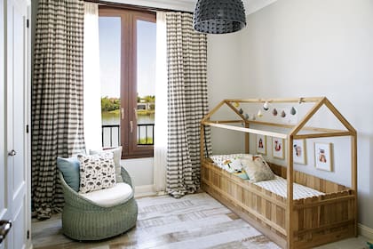 La cama-casita Montessori, el sillón panzón de mimbre y las cortinas rayadas son de Mesopotamia.