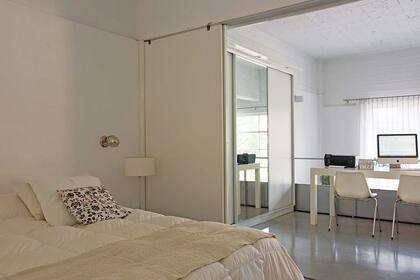 La cama está vestida con acolchado y almohadones traídos la casa de Pilar. Los apliques cromados ya estaban en el dúplex