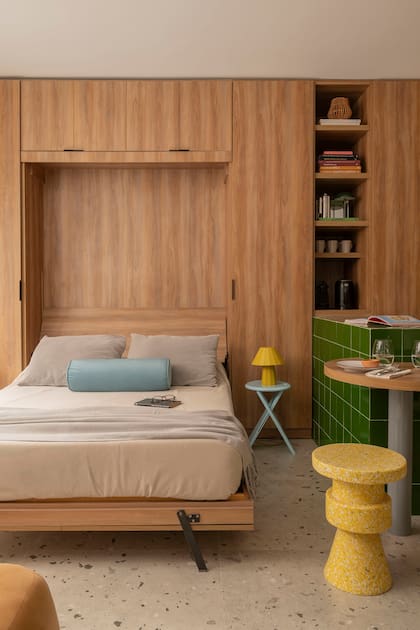 La cama rebatible era original del monoambiente, pero se revistó en melamina y anexó al mueble que atraviesa el ambiente al lo largo. Pisos porcelanato (Vite) banqueta (Par en Par)