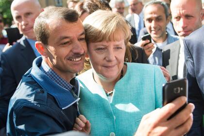 La canciller alemana Angela Merkel se toma una selfie con un refugiado en el centro de recepción de refugiados en Berlín, Alemania, el 10 de septiembre de 2019. (Bernd von Jutrczenka/dpa via AP, File)