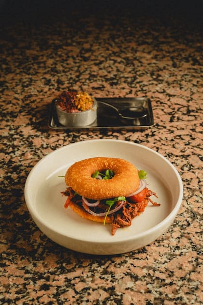 La carne del bagel de carnitas se marina durante 24 horas en un adobo de vegetales, hierbas y especias