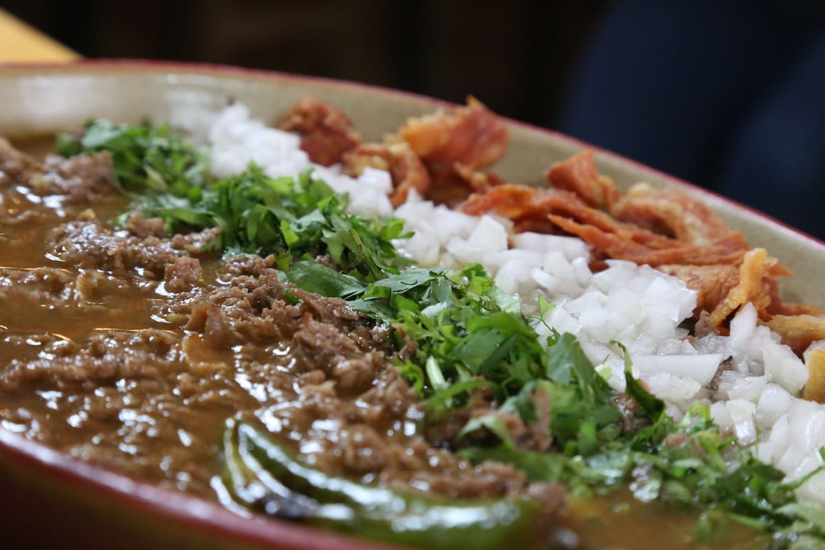 La carne en su jugo es un platillo de Guadalajara que mezcla tiras de res, tocino y salsa de tomatillo, servida con frijoles y guarniciones frescas