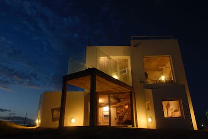 La casa brilla en la oscuridad, destacando su diseño contemporáneo y su conexión armoniosa con el paisaje costero de Mar del Sud