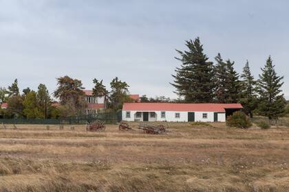 La casa grande de la estancia se erige detrás de los árboles.