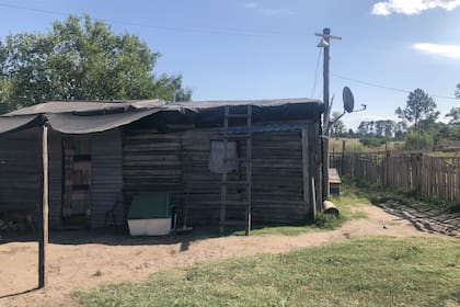 La casilla en la que vive está hecha de paredes de madera fina, el techo está cubierto con lijas y bolsas de plástico para que no entre el agua. Tienen luz y agua. El baño está adentro pero es de madera y necesitan cambiarlo