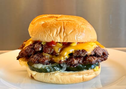La Cheeseburger de Grasa con medallón smash simple o doble, cheddar, pickles de pepino, mostaza, ketchup y cebolla