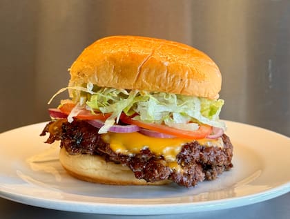 La Clásica de Grasa con medallón smash simple o doble, cheddar, lechuga, tomate, cebolla y salsa de la casa