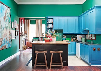 La cocina abierta, entre el comedor y el estar. Antes blanca de piso a techo, Sarah le imprimió un intenso contraste con paredes de un verde bien inglés y muebles en azul.