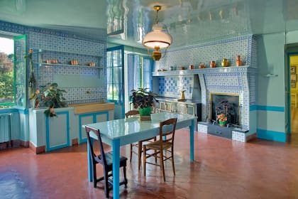 La cocina con chimenea, en azulejos azules Rouen, contrasta con los tonos cálidos del estar y el amarillo del comedor.