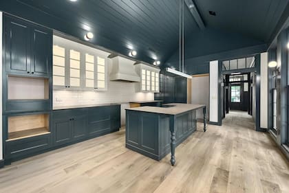 La cocina cuenta con muebles en tonos oscuros, electrodomésticos empotrados y pisos de madera clara