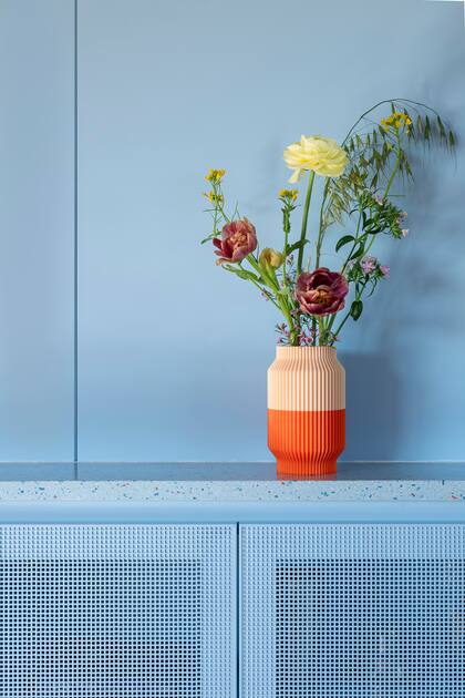 La cocina del departamento está abierta a un comedor con una paleta coral, de ahí el juego de colores que se propone en los floreros.
