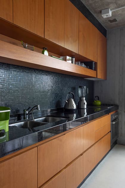 La cocina mantuvo la estructura original y sintetizó su paleta con una alzada de venecitas negras, de modo que prácticamente desaparece en la vista general del ambiente.