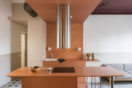 La cocina se transformó en un bloque abierto pero compacto usando el mismo tono terroso desde el piso, pasando por la alzada de la pileta (ambos, en microcemento), los muebles bajo-mesada hasta el techo y la barra del otro lado.